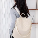 Morral para dama color beige con diseño a cuadros, cierre superior y correas ajustables.