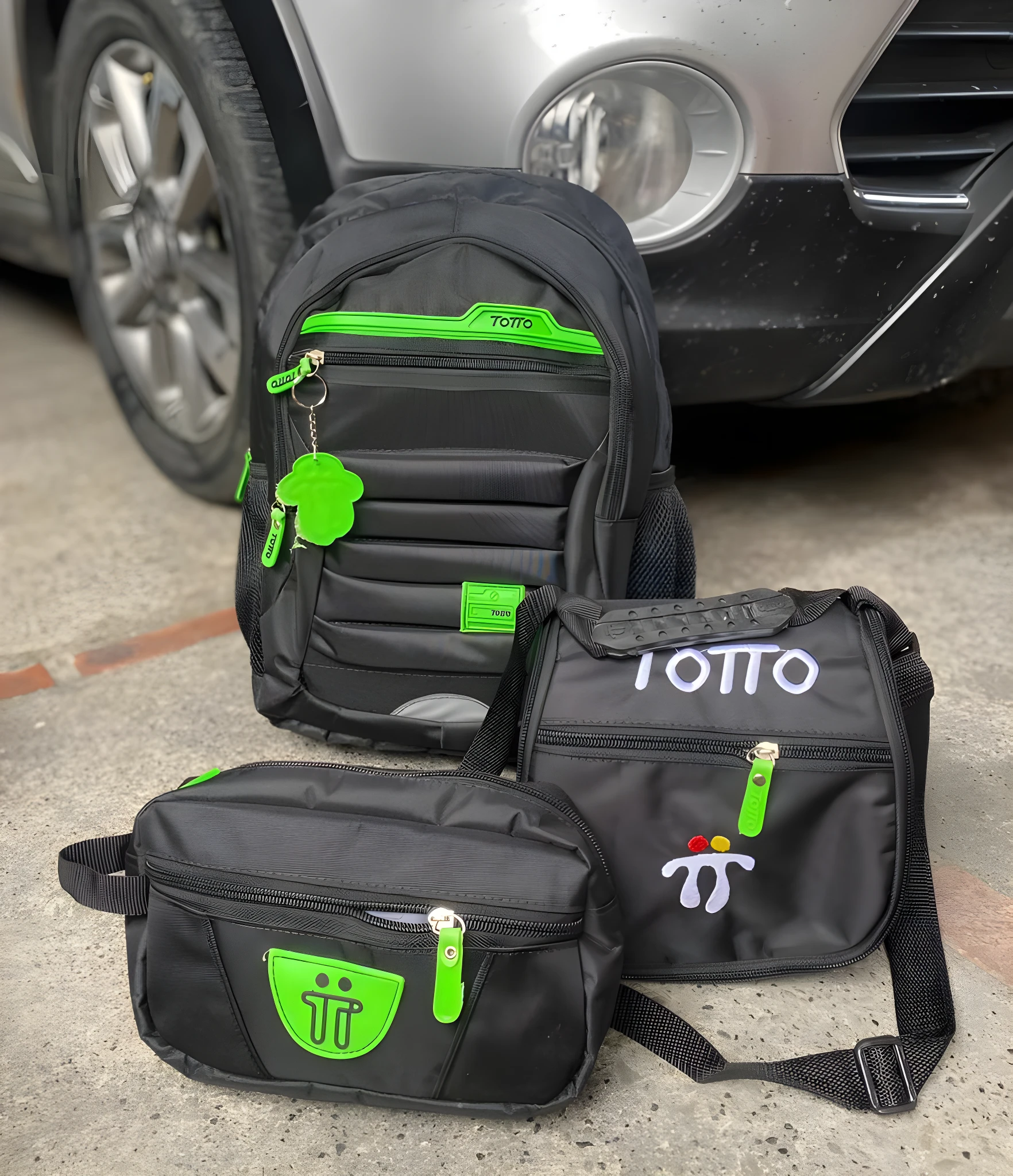 Set de morral, cartuchera y lonchera Totto negros con detalles y logos en verde neón.