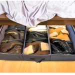 Organizador bajo cama gris con 4 compartimentos, lleno de botas de invierno y botines, ideal para almacenar calzado.
