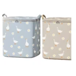 Dos canastas organizadoras de ropa grandes, plegables, con tapa de cremallera y asas. Una azul claro y otra beige, ambas con estampado de gansos blancos y margaritas.
