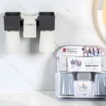 Organizador de baño montado en pared con dos compartimentos oscuros y vasos blancos invertidos. Empaque muestra variante gris y azul.