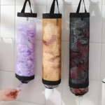 Tres dispensadores verticales de malla para bolsas plásticas: uno transparente con bolsas moradas, uno dorado y uno negro, colgados en pared de azulejos blancos.