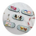 Cinco organizadores de cable tipo patineta, base celeste, con figuras 3D Disney: Lotso, Mickey y Minnie, Daisy y otro personaje, y dos osos.