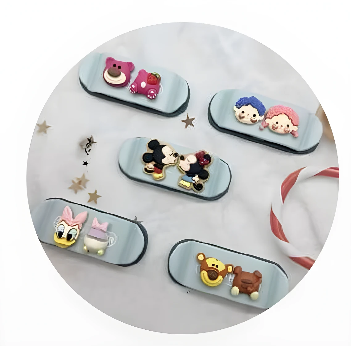 Cinco organizadores de cable tipo patineta, base celeste, con figuras 3D Disney: Lotso, Mickey y Minnie, Daisy y otro personaje, y dos osos.