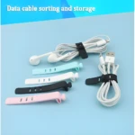 Sujetacables de silicona elásticos en colores negro, azul claro, blanco y rosa, organizando audífonos y cable USB.