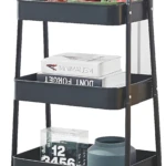 Carro organizador negro de 3 niveles con conejo decorativo, libros y frutas.