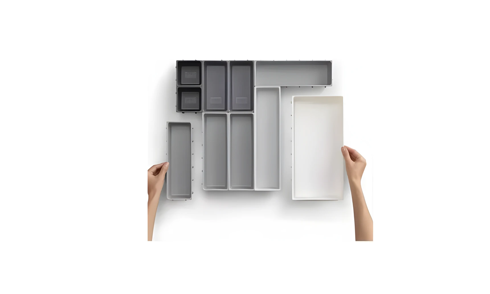 Organizador de cubiertos gris y blanco, varias secciones, manos acomodando las piezas.