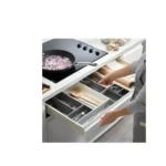 Organizador de cubiertos gris y blanco en cajón de cocina con utensilios y rodillo para amasar.