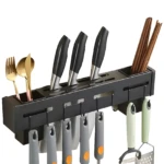 Organizador negro de pared para cuchillos, cubiertos dorados, palillos y utensilios de cocina.