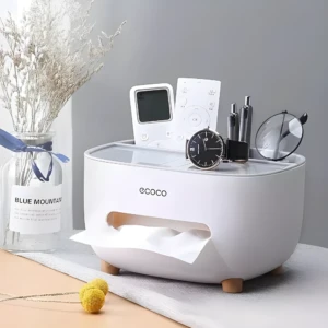 Organizador de escritorio blanco con dispensador de pañuelos y compartimentos para controles, bolígrafos y reloj.