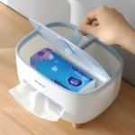 Organizador blanco y azul para escritorio con tapa abierta, dispensador de pañuelos y compartimentos para controles y bolígrafos.