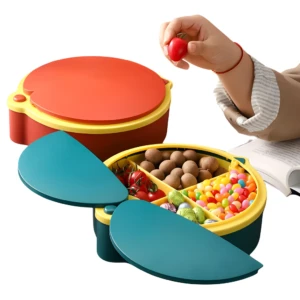 Contenedor redondo de 4 espacios para frutas, color naranja y turquesa, con tapas abiertas mostrando dulces y tomates.