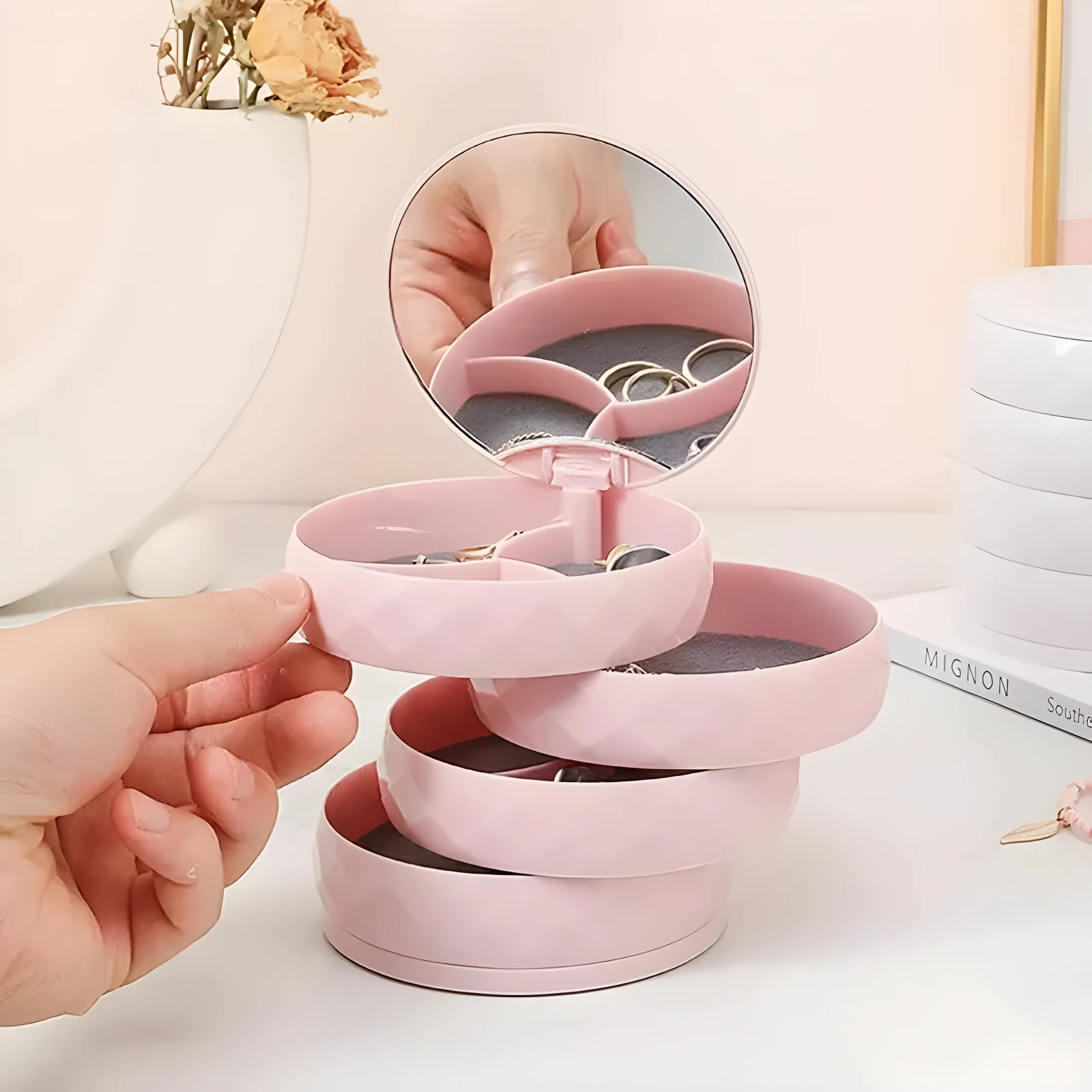 Organizador de joyas compacto rosa con espejo y compartimentos giratorios.