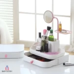 Organizador de maquillaje blanco con espejo giratorio, compartimentos y cajón para cosméticos y accesorios.