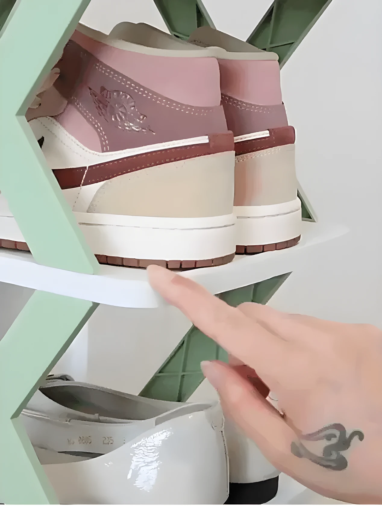 Zapatillas deportivas color rosa y beige sobre organizador de zapatos multiestante verde y blanco.