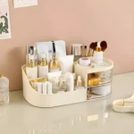 Organizador de cosméticos beige tipo O en tocador con botellas, brochas, labiales y cajones transparentes.