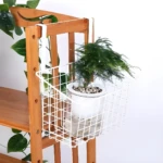 Canasta de alambre blanca colgante para gabinete con planta en maceta, maximiza espacio.