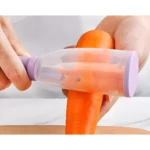 Manos pelando una zanahoria grande con pelador de plástico translúcido con tapa lila, recolectando las cáscaras.