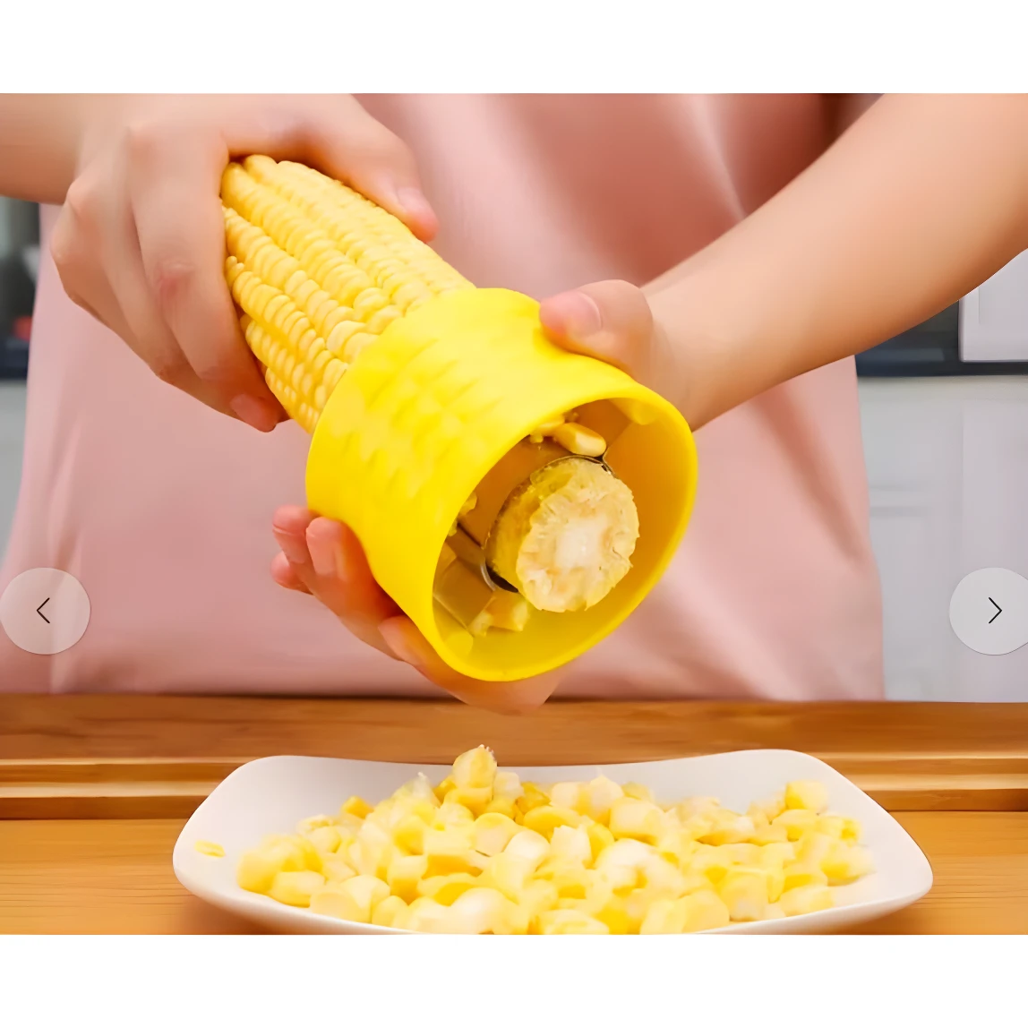 Manos usando desgranador amarillo para quitar granos de maíz a una mazorca sobre plato blanco con maíz suelto.