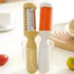 Pelador amarillo con cuchilla y cepillo naranja, ideal para cocina.