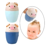 Regadera de baño para bebé con forma de cerdito en colores azul claro y azul oscuro, vertiendo agua sobre la cabeza de un niño sonriente.