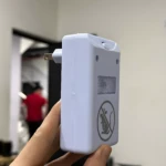 Repelente ultrasónico Ridex blanco, mostrado de cerca en mano, con símbolo de no ratones y enchufe visible.