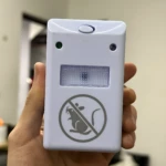 Repelente ultrasónico blanco Ridex en mano, mostrando botón superior, dos LEDs y pictograma de rata prohibida.