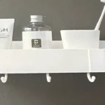Repisa lineal blanca para baño con jabón líquido, cepillo y vaso, ideal para organizar la ducha.