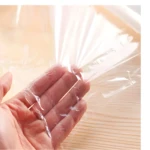 Mano sosteniendo y separando suavemente película plástica transparente arrugada sobre superficie de madera clara.