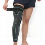 Rodillera compresión extra larga gris y verde ajustándose con banda de sujeción superior en muslo.