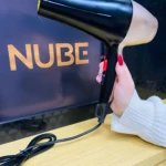 Secador profesional negro y dorado de mano, con cable negro, mostrando el logo NUBE.