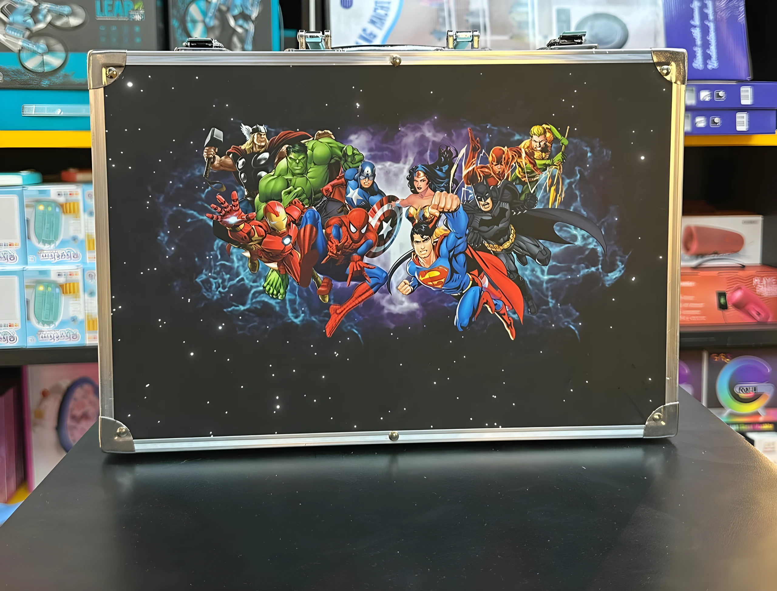 Maleta metálica negra con diseño de superhéroes de cómic, ideal para arte.