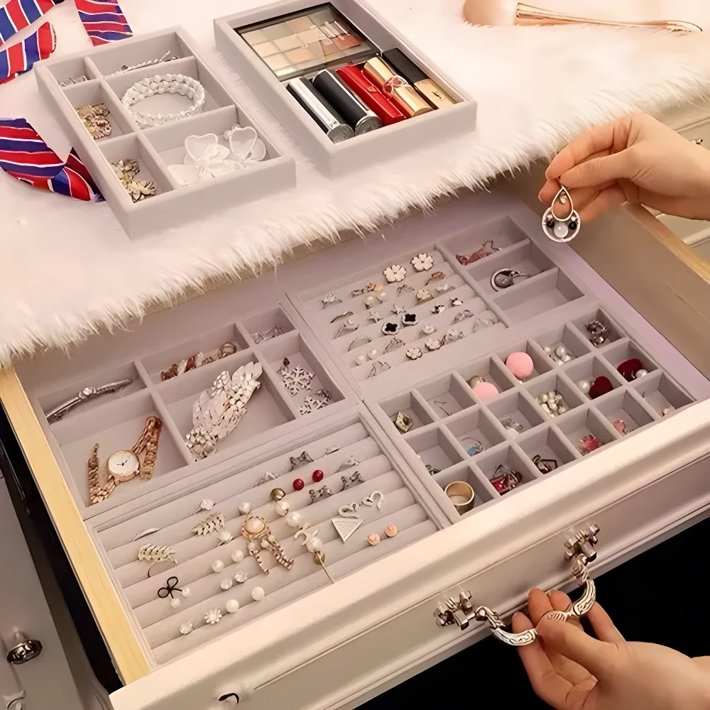 Set joyero apilable gris con organizadores de compartimentos llenos de joyas, maquillaje y aretes.