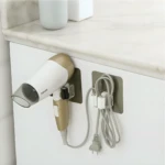 Soporte organizador de pared para secador de cabello y cables, color gris y blanco.
