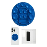 Soporte circular azul con múltiples ventosas y soporte plegable, fijado a funda blanca de celular y adherido a pared blanca.