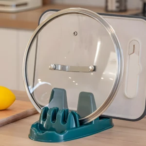 Soporte verde para tapas y utensilios de cocina, con limón en tabla al lado.