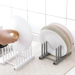 Dos soportes escurridores para platos: uno blanco sosteniendo una tapa de olla con agarre de madera, y otro gris con platos apilados.