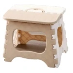 Taburete plegable portátil color beige y blanco, plástico, con superficie texturizada y asa para transportar.
