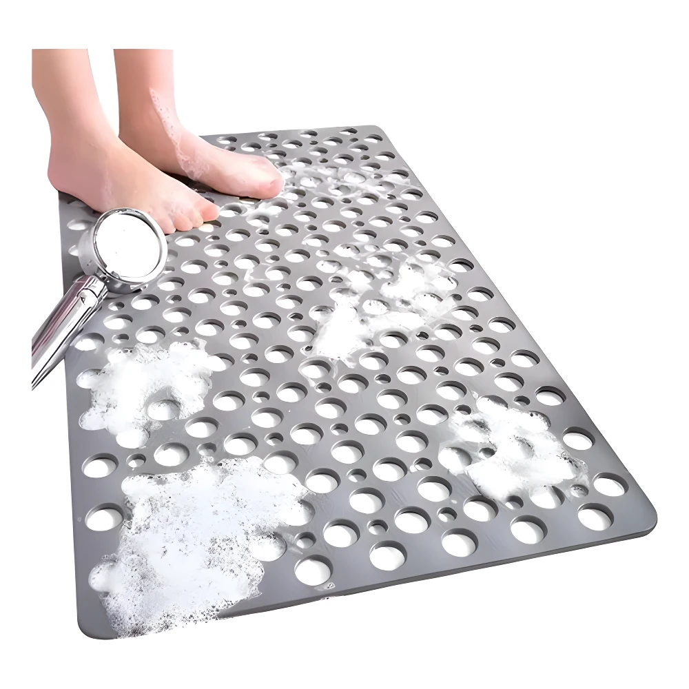 Tapete antideslizante gris con orificios para ducha, pies descalzos mojados y jabón.