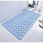 Tapete de ducha azul claro con textura perforada, antideslizante, ubicado en suelo de baño blanco junto a una bañera y dispensadores de jabón.