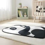 Tapete decorativo blanco y negro con diseño de cabeza de panda sobre alfombra mullida clara, junto a cuna de madera y estantería.