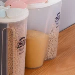 Tarros organizadores de cocina transparentes, uno con lentejas y marca "2500", otro con polvo amarillo.