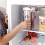 Tarro organizador transparente para cocina con dos compartimentos para granos y medidas visibles.