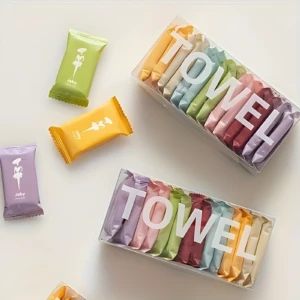 Caja transparente con toallas faciales comprimidas de algodón en colores pastel y blanco, ideales para viaje.