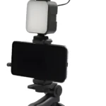 Trípode negro portátil con micrófono, luz y soporte para celular para vlogs.