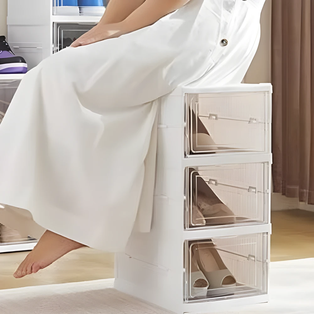 Zapatero plegable blanco de 3 niveles con puertas transparentes, mostrando zapatillas y tacones.