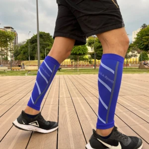 Pantorillera de compresión running azul con diseño de rayas plateadas, para hombre, vista a nivel de pierna.