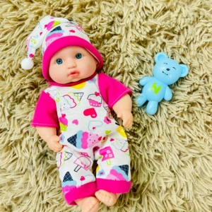 Bebe de juguete con pijama de dulces y osito azul sobre alfombra peluda.
