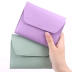 Set de 2 estuches de aseo, uno lila y otro verde menta, ambos con cierre de solapa y costuras visibles, sostenidos por una mano.