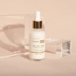 Sérum facial Bio-Retinol DERMOHELP en frasco de vidrio con gotero dorado, entre bloques acrílicos.